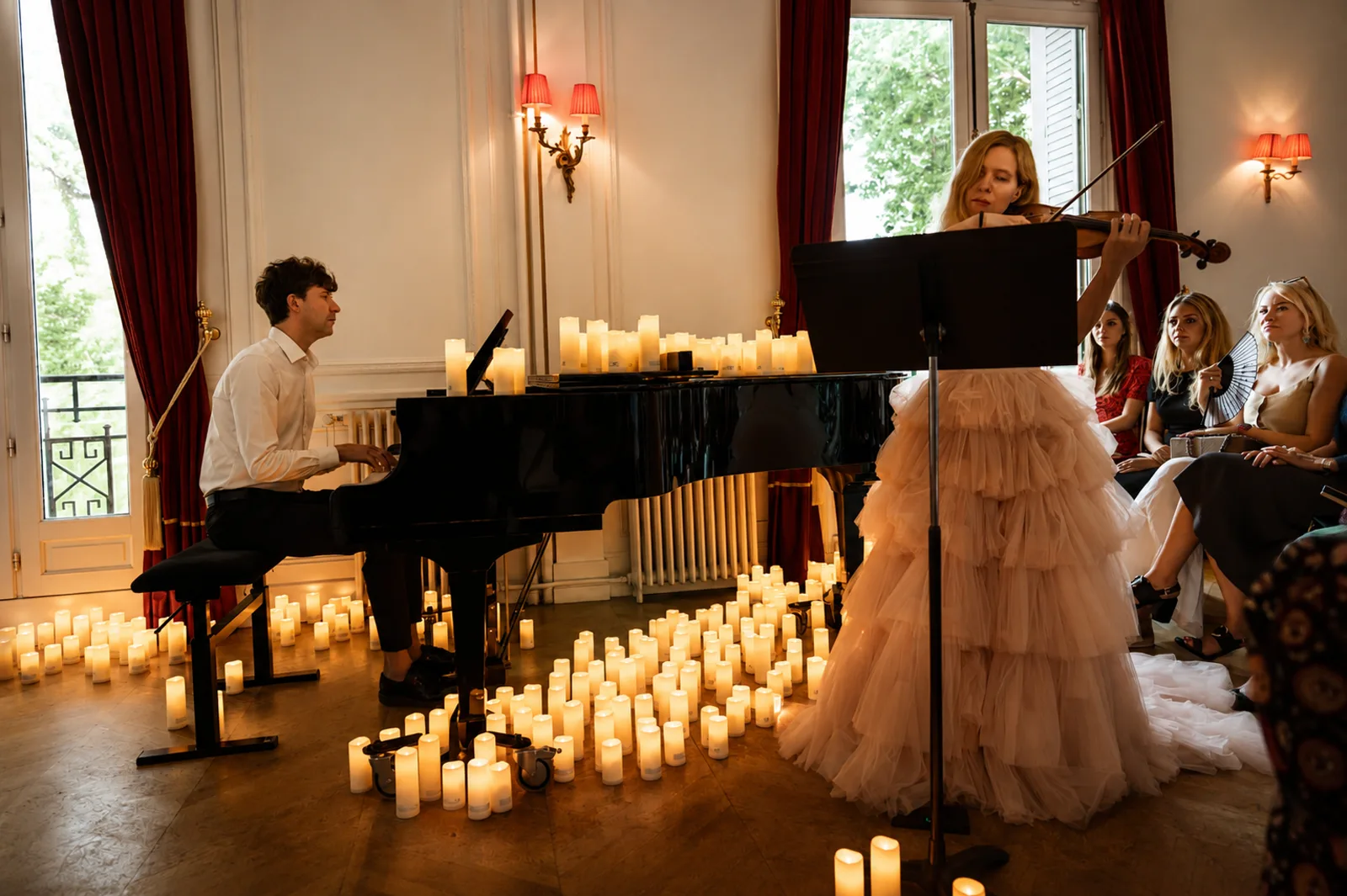 Concert intimiste aux chandelles — piano et violon dans un salon, auditoire à proximité