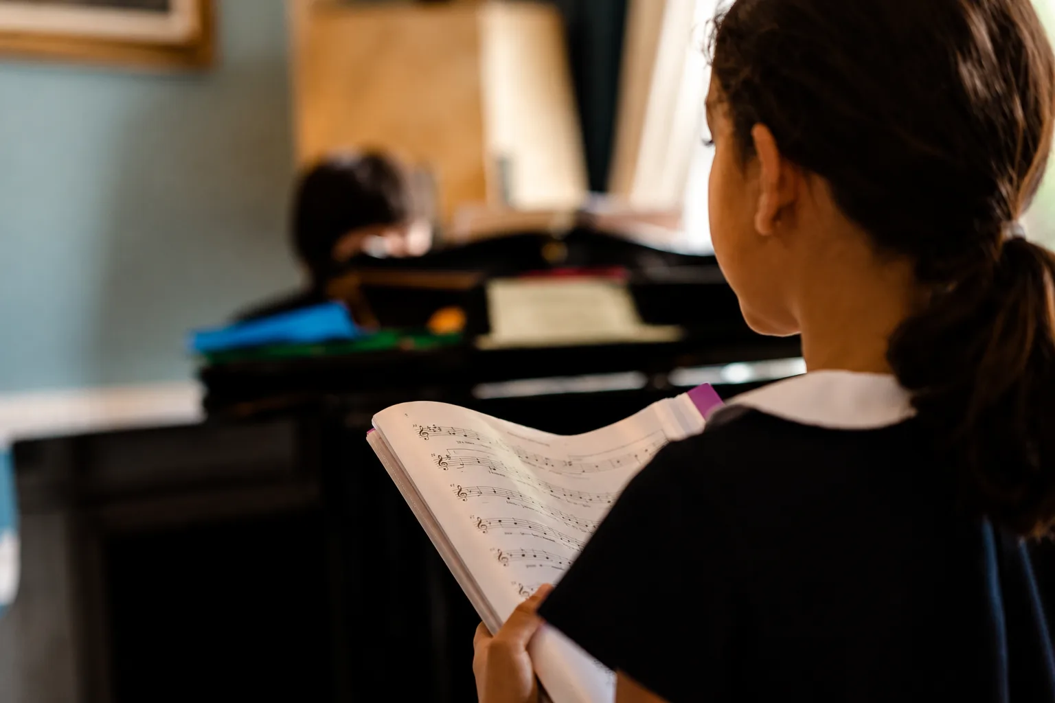 Jeune élève suivant la partition pendant qu'un autre joue au piano