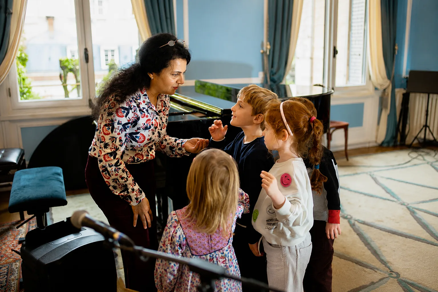 Professeure accompagnant un groupe d'enfants devant un piano dans un salon de l'Institut